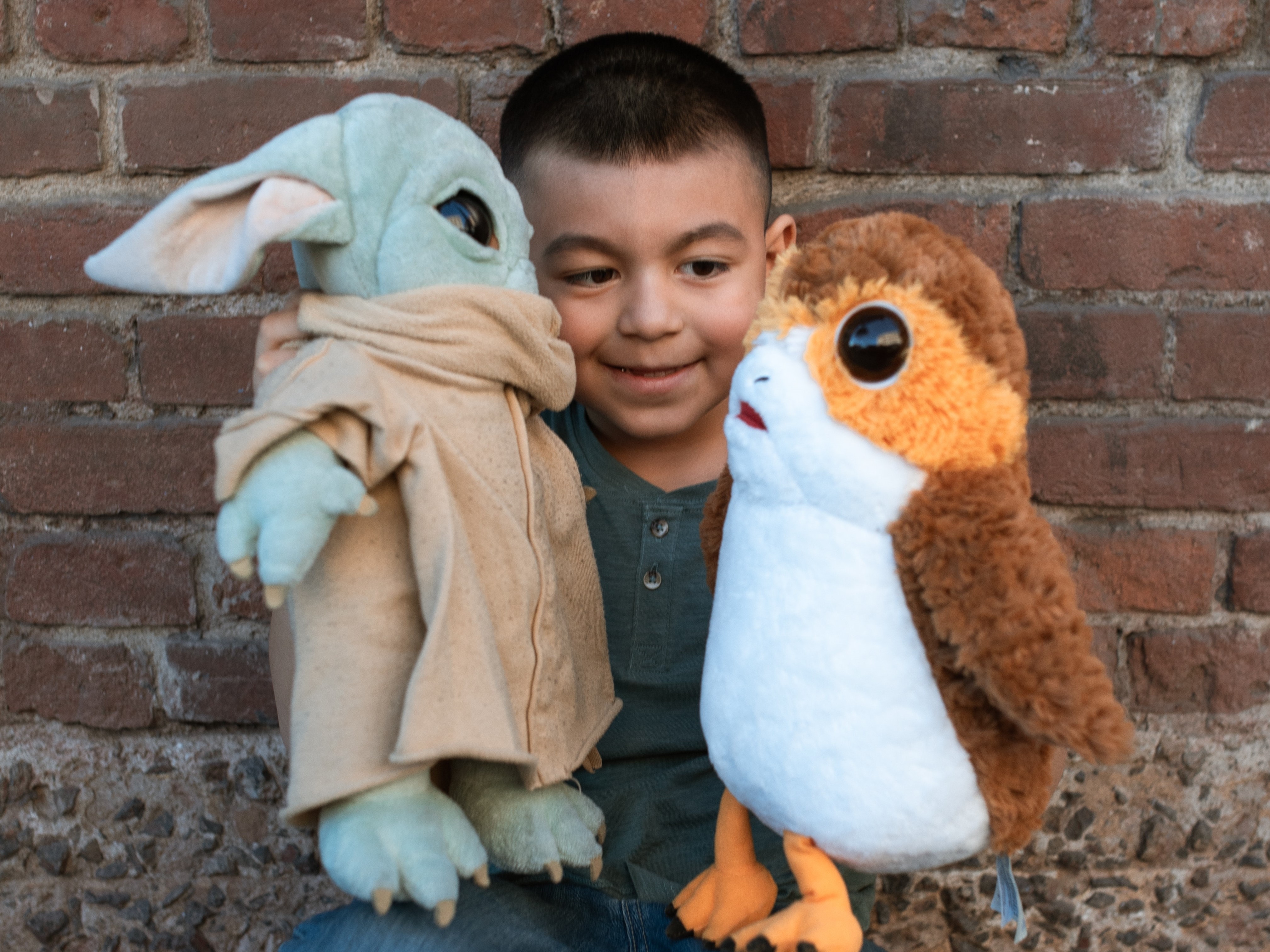 cute Latino boy playing with two toys, making them have a conversation